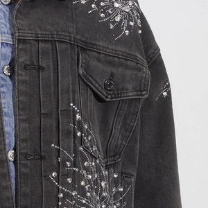 Détail d'une veste en jean noir lavé avec des motifs d'étoiles en strass étincelants