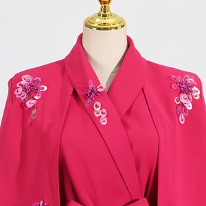 Detail of handmade pink sequins and floral beadwork on a rose red cloak-style jacket