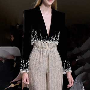 Detail of black velvet blazer with crystal fringe tassels and wide leg silver trousers