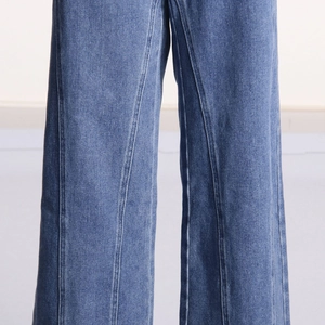 Gros plan détaillé montrant la double couture verticale sur un jean droit bleu délavé