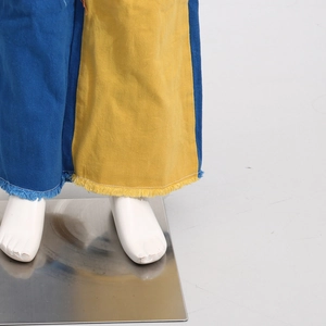 Detail of frayed hem and blue-yellow color block patchwork on straight leg jeans