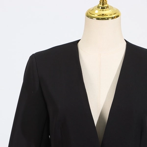Detail of black deep V-neck collarless blazer with premium tailored shoulder structure