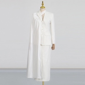 Detail of white blazer set featuring a unique asymmetric draped satin shoulder cape