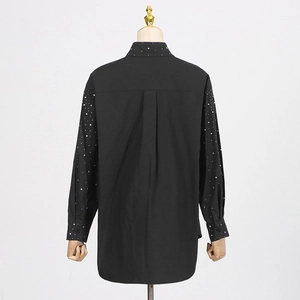 Detail of rhinestone embellishments on collar and back pleat of a black long-sleeve shirt