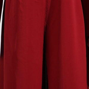 Détail de la frange à bord brut vertical sur le tissu d'un manteau long rouge foncé