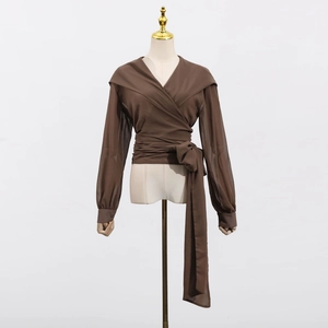 Detail of dark coffee wrap top featuring long sheer sleeves and side tie ribbon waist