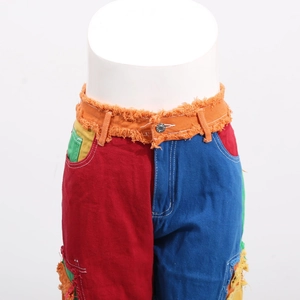 Detail view of multi-color patchwork denim with frayed orange waist and metal button