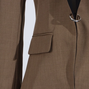 Close-up of brown blazer featuring a unique silver metal ring buckle and flap pocket