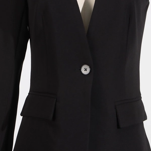 Detail of black blazer waist showing single button closure and flap pockets