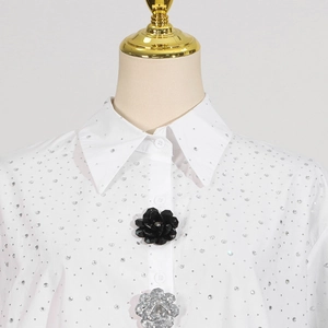 Detail of white shirt with shimmering rhinestones and black silver 3D floral accents