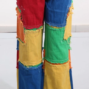 Detail view of colorful patchwork denim jeans with frayed edges and retro street style
