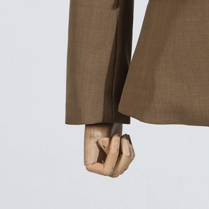 Detailed macro shot of brown suit jacket sleeve and hem texture on wooden mannequin