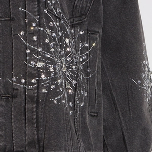 Gros plan de strass étincelants et perles blanches sur tissu de veste en jean gris