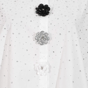 Macro shot of floral decorative buttons and glittering rhinestones on a white blouse