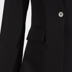 Close-up of black suit jacket detail showing grey button and flap pocket craftsmanship