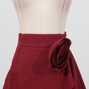 Détail de la jupe taille haute rouge foncé avec une grande rose décorative en tissu 3D