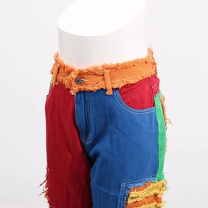 Detailed view of colorful patchwork denim jeans featuring distressed frayed edge textures