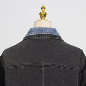 Détail du col en jean bleu clair contrastant sur une veste en jean gris foncé avec coutures
