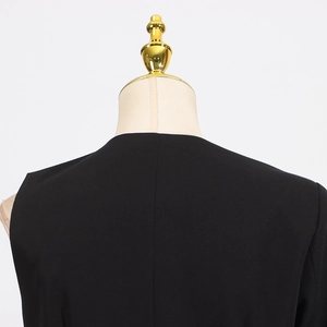 Detail view of the black irregular top made of smooth woven suit fabric on a mannequin