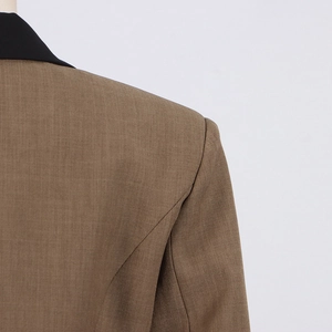 Detailed close-up of brown blazer with black contrast lapel and textured woven fabric
