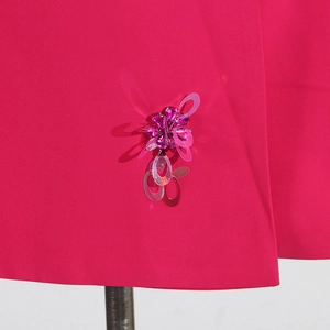 Macro detail of 3D sequin flower embellishment on a magenta tailored blazer