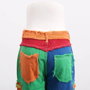 Detailed view of color-block patchwork jeans with distressed frayed edges and vibrant panels