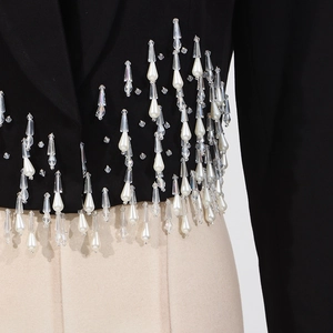 Close-up of black blazer with luxury crystal beads and white pearl fringe details