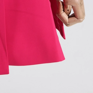 Close-up of rose red blazer fabric showing smooth weave texture and clean hemline detail