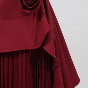 Détail de jupe plissée rouge vin avec fleur 3D et coupe asymétrique multicouche élégante