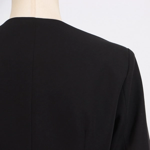 Detailed back view of high-density black fabric with stitching on a collarless top