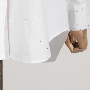 Macro view of white shirt hem and cuffs featuring shimmering silver rhinestone embellishments