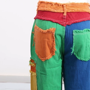 Detail of colorful patchwork denim with raw frayed edges and high-contrast stitching