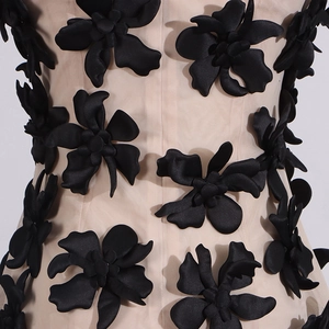 Detailed close-up of 3D black flower appliques on beige mesh fabric of a sleeveless top