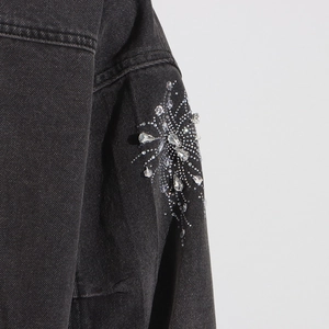 Détail de strass étincelants et perles argentées sur la manche d'une veste en jean