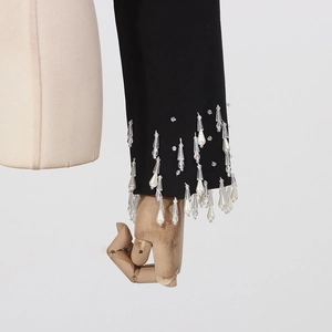 Detail of beaded fringe and pearl tassels on black blazer sleeve with intricate craftsmanship