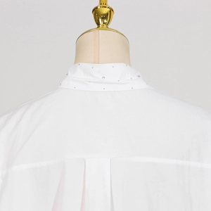 Detail of white button-up shirt featuring sparkling rhinestone embellishments on the collar