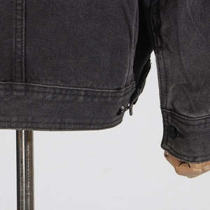 Détail des boucles métalliques et coutures sur l'ourlet de la veste en jean noir