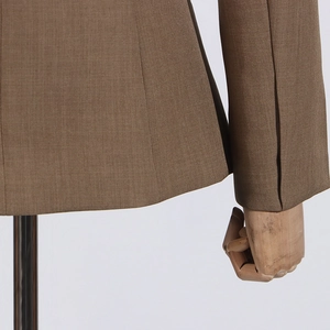 Detail view of brown blazer featuring a refined twill texture and split cuff design