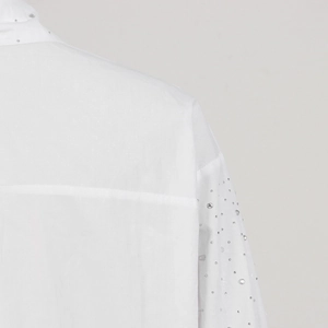 Close-up of sparkling rhinestones on the collar and sleeve of this white fashion blouse