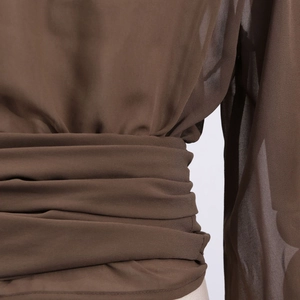 Close-up of brown chiffon top showing layered waist pleats and sheer fabric texture