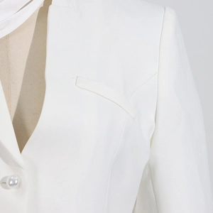 Close-up of white blazer jacket with stylish pearl button and modern lapel detail