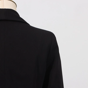 Detailed view of black blazer shoulder stitching and lapel fold on professional mannequin