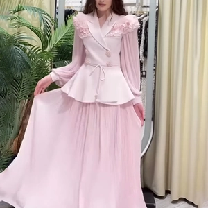 Detail of pink suit top with ruffled shoulders and elegant pleated skirt matching set