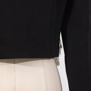 Detailed close-up of beaded fringe and crystal tassels on a black cropped blazer