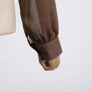 Detail of dark brown sheer chiffon shirt sleeve with pleated elastic cuffs on a mannequin