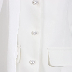 Detail of white blazer with elegant pearl buttons and symmetrical flap pockets