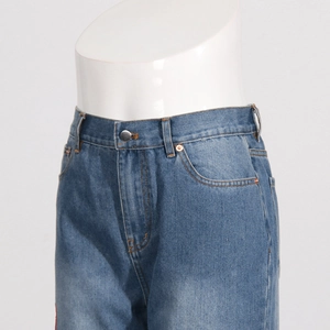 Detail of blue denim jeans featuring a high waist, metal button, and washed texture