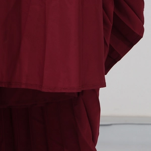 Détail du tissu plissé bordeaux avec des coutures fines sur la jupe longue élégante