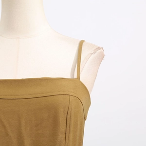 Detail of olive green jumpsuit featuring slim straps and a flat neckline on a mannequin