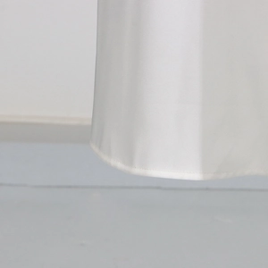 Close-up of white satin fabric showing smooth texture and fine hemline stitching detail